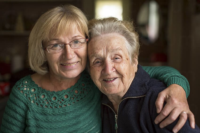 Mujer abrazando a su madre anciana